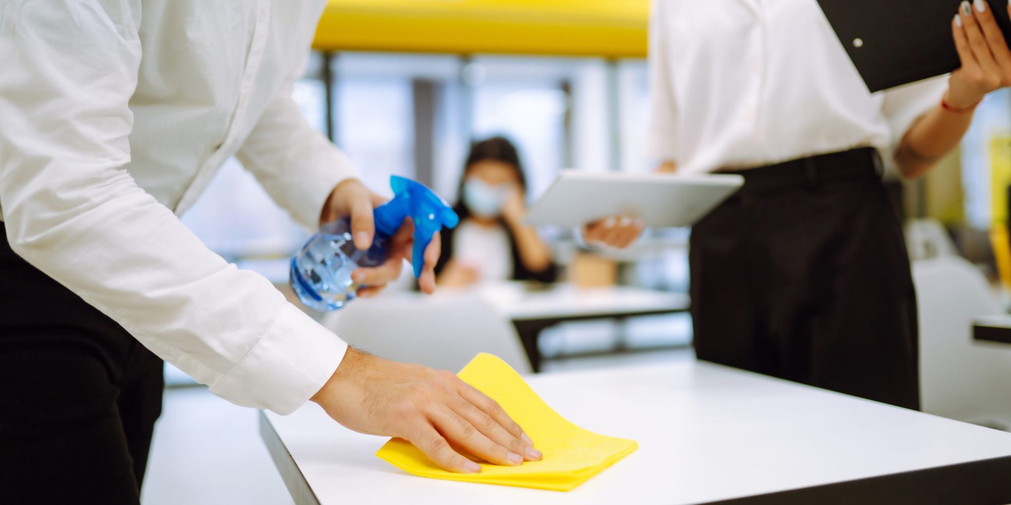 Cleaning and disinfection of the desktop. Man in protective sterile mask cleans the working desk.